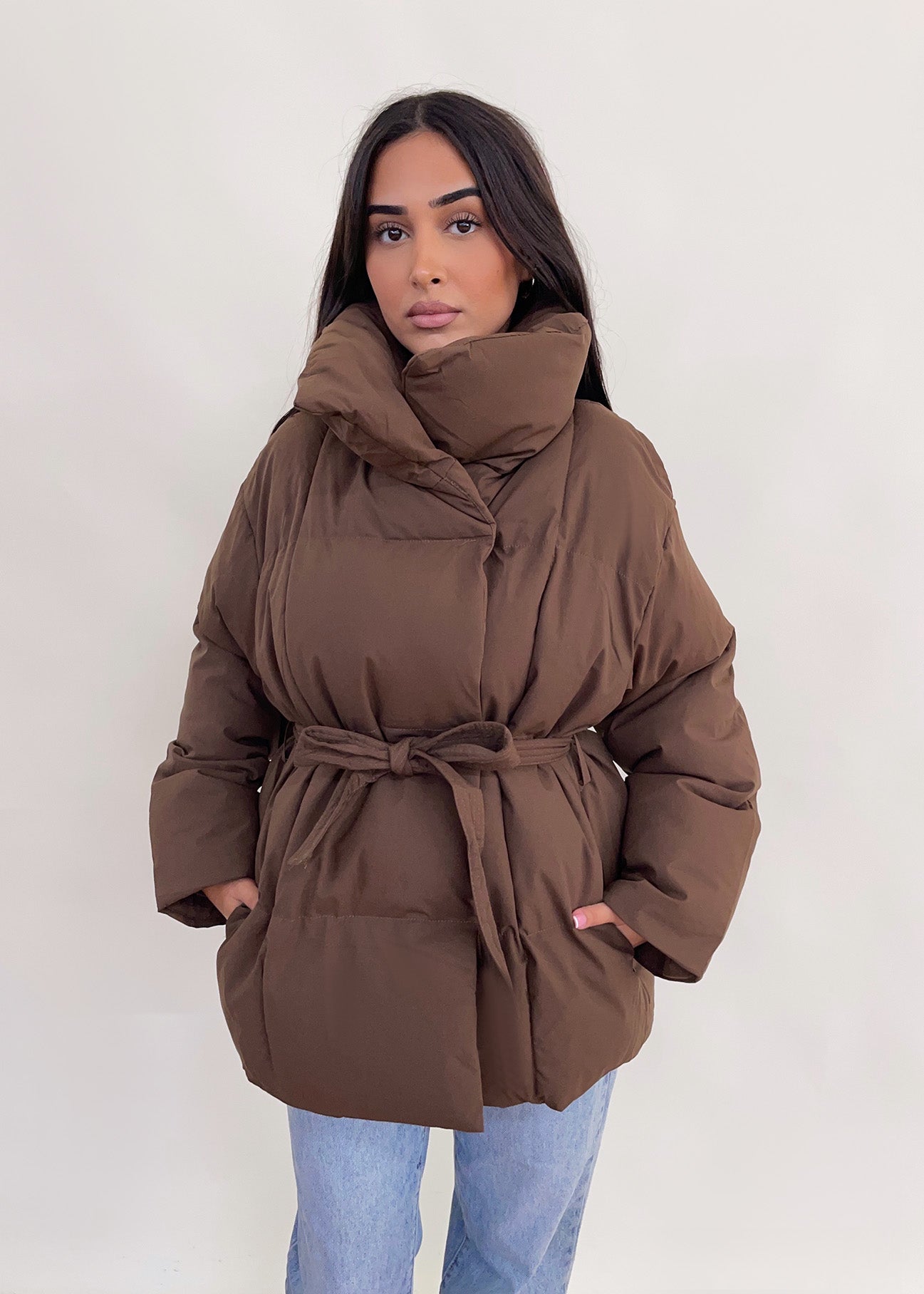Modell trägt eine kurze Damen Steppjacke mit Taillengürtel – NAHA Fashion