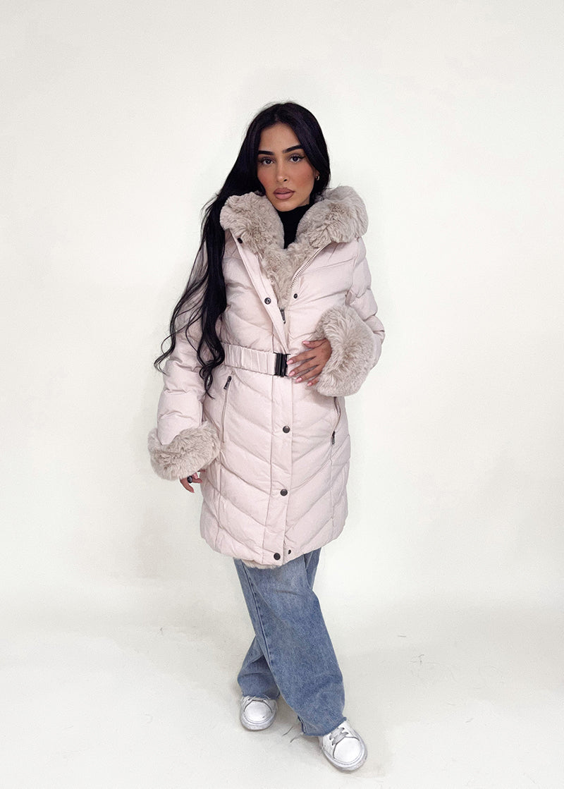 Modell trägt eine taillierte Damen Steppjacke mit Gürtel, Fellkragen und Fellärmeln – NAHA Wintermode