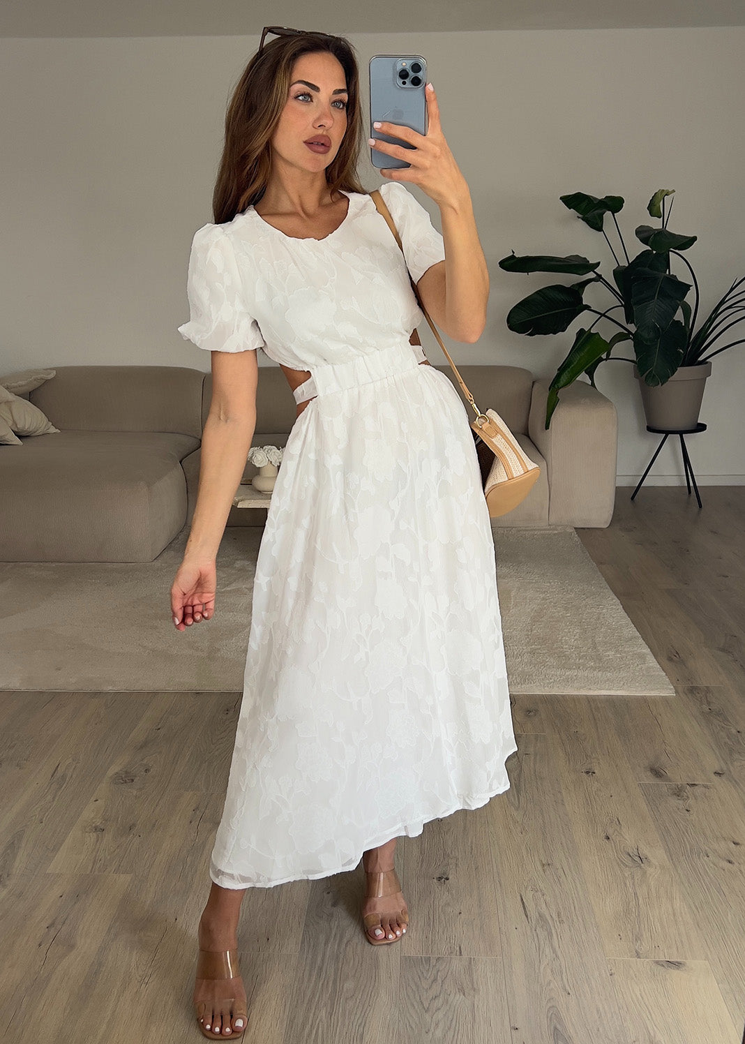 Frau trägt ein weißes Kleid mit Puffärmeln und tailliertem Schnitt – Sommermode von NAHA