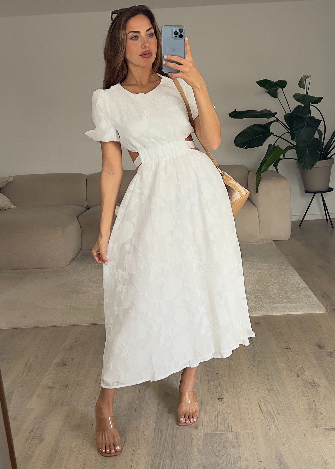 Frau trägt ein weißes Kleid mit Puffärmeln und tailliertem Schnitt – Sommermode von NAHA