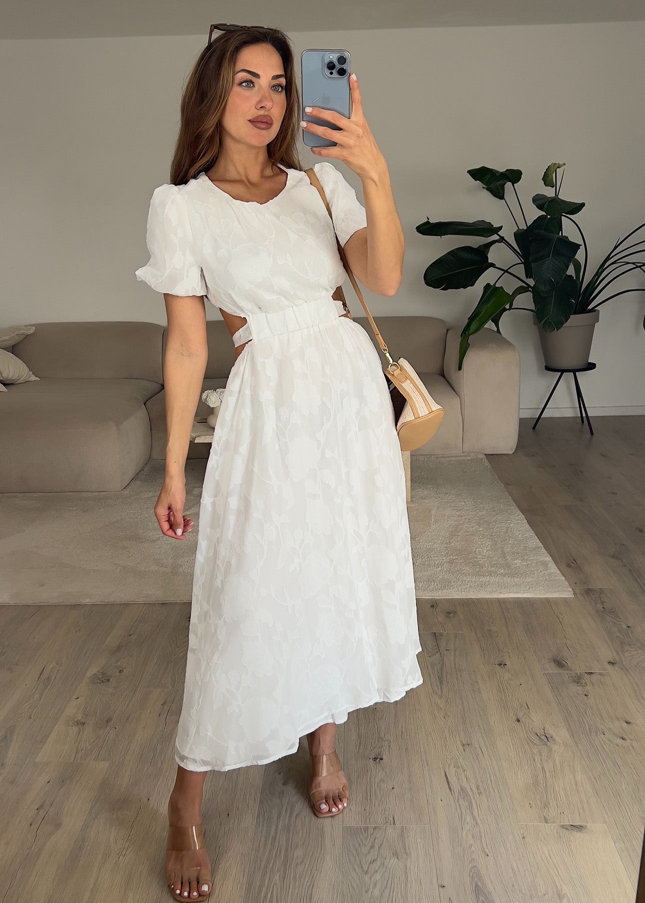 Frau trägt ein weißes Kleid mit Puffärmeln und tailliertem Schnitt – Sommermode von NAHA