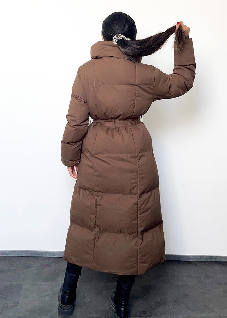Frau trägt braune Winterjacke mit Gürtel & Stehkragen – gesteppt & warm von NAHA