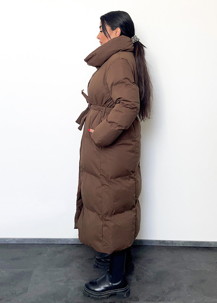 Frau trägt braune Winterjacke mit Gürtel & Stehkragen – gesteppt & warm von NAHA