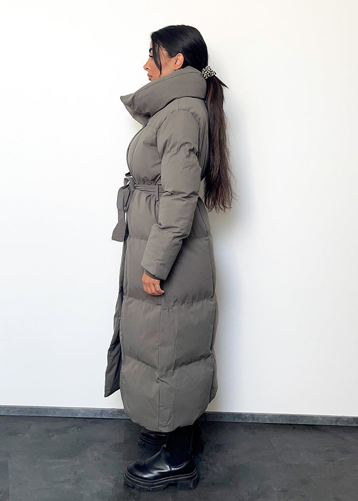 Frau trägt lange graue Winterjacke mit Gürtel & Stehkragen – moderner Winterlook von NAHA