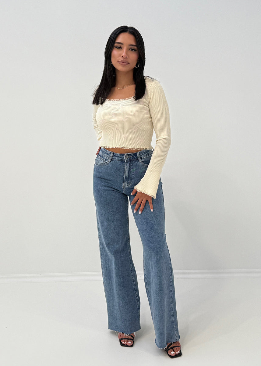 Modell trägt Langarm-Ripp-Oberteil mit Zierschleifen und ausgestelltem Ärmelabschluss