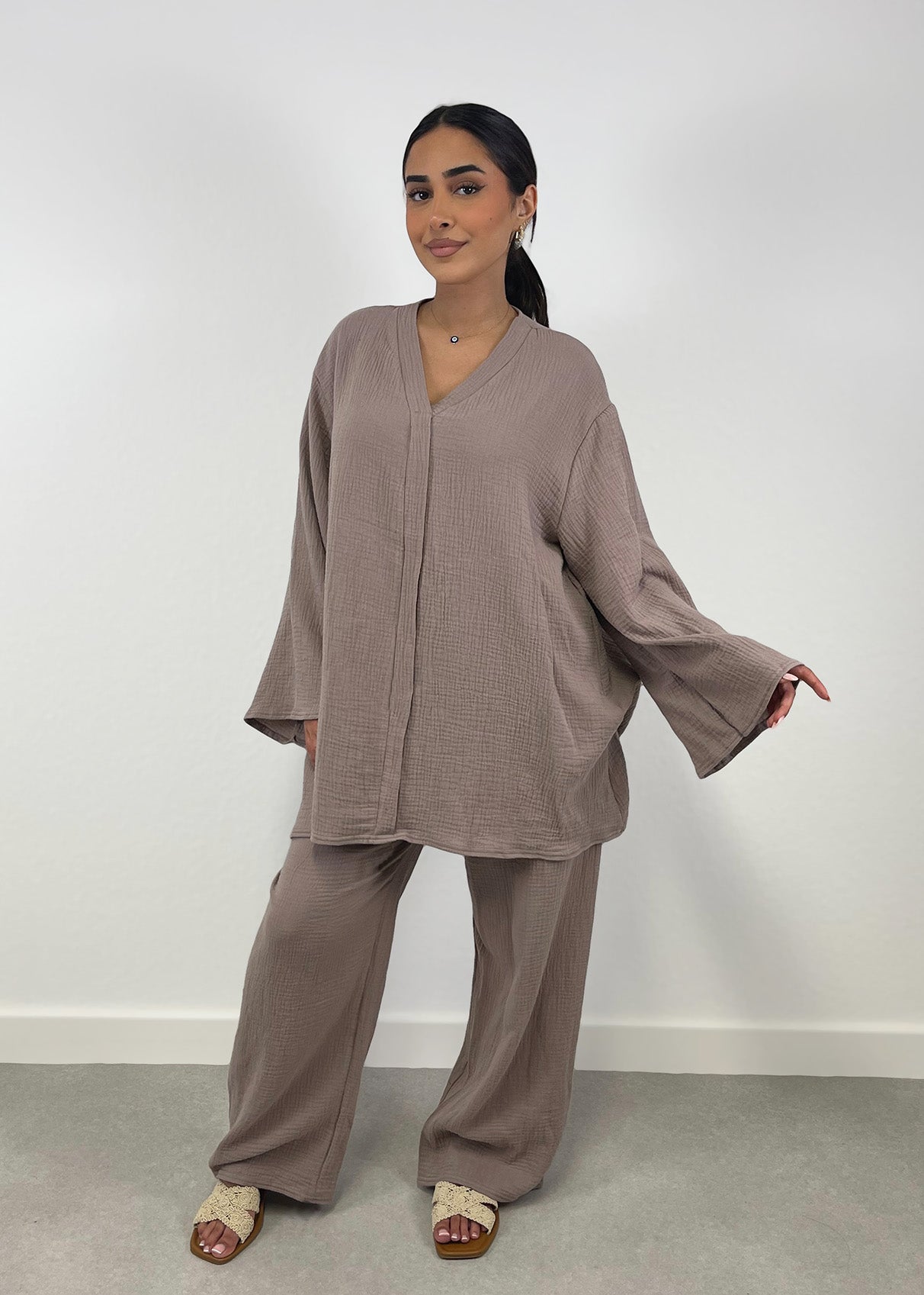 Frau trägt taupefarbenen Musselin-Zweiteiler mit weiter Hose und Oversize-Bluse
