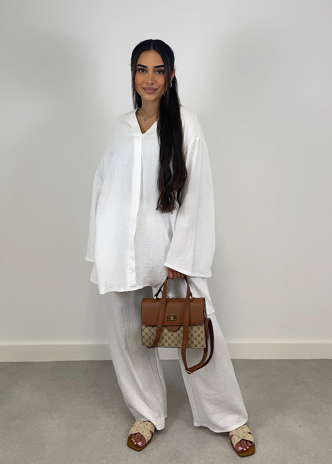Frau trägt weißen Zweiteiler aus Musselin mit weiter Hose und Oversize-Bluse