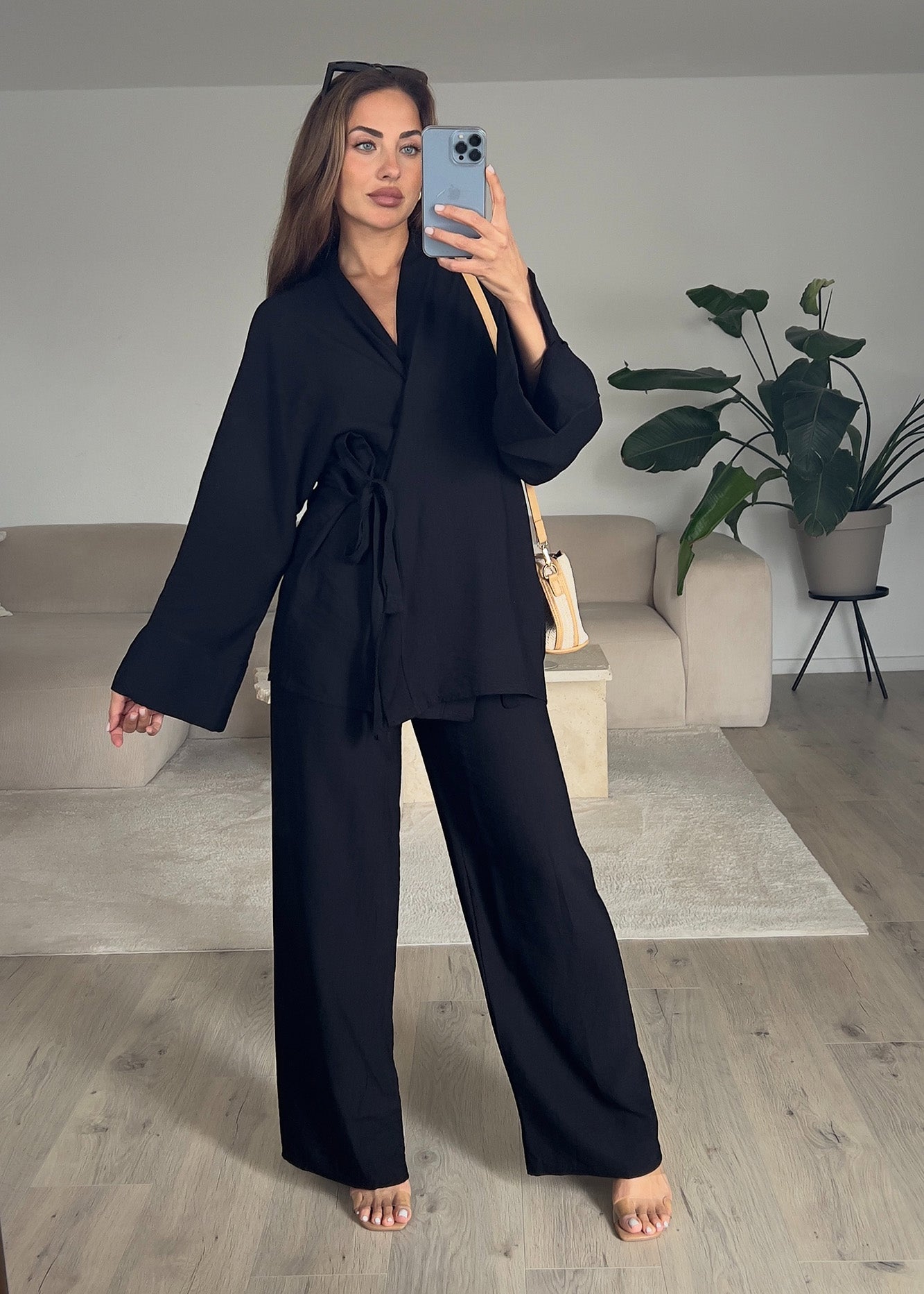 Modell trägt einen Basic-Zweiteiler in Wickeloptik in Schwarz – mit Wickeloberteil und weiter Hose