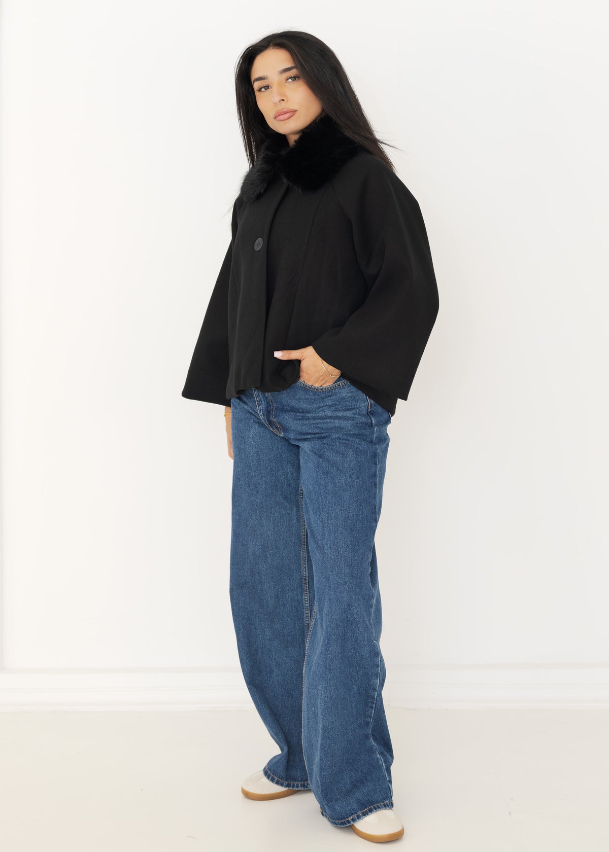 Seitenansicht der schwarzen Capejacke mit weiten Fledermausärmeln und cropped Länge