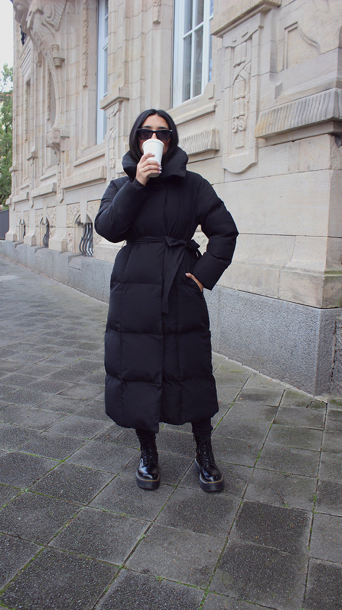 Damen lange Winterjacke in Schwarz – Vorderansicht mit Bindegürtel – NAHA