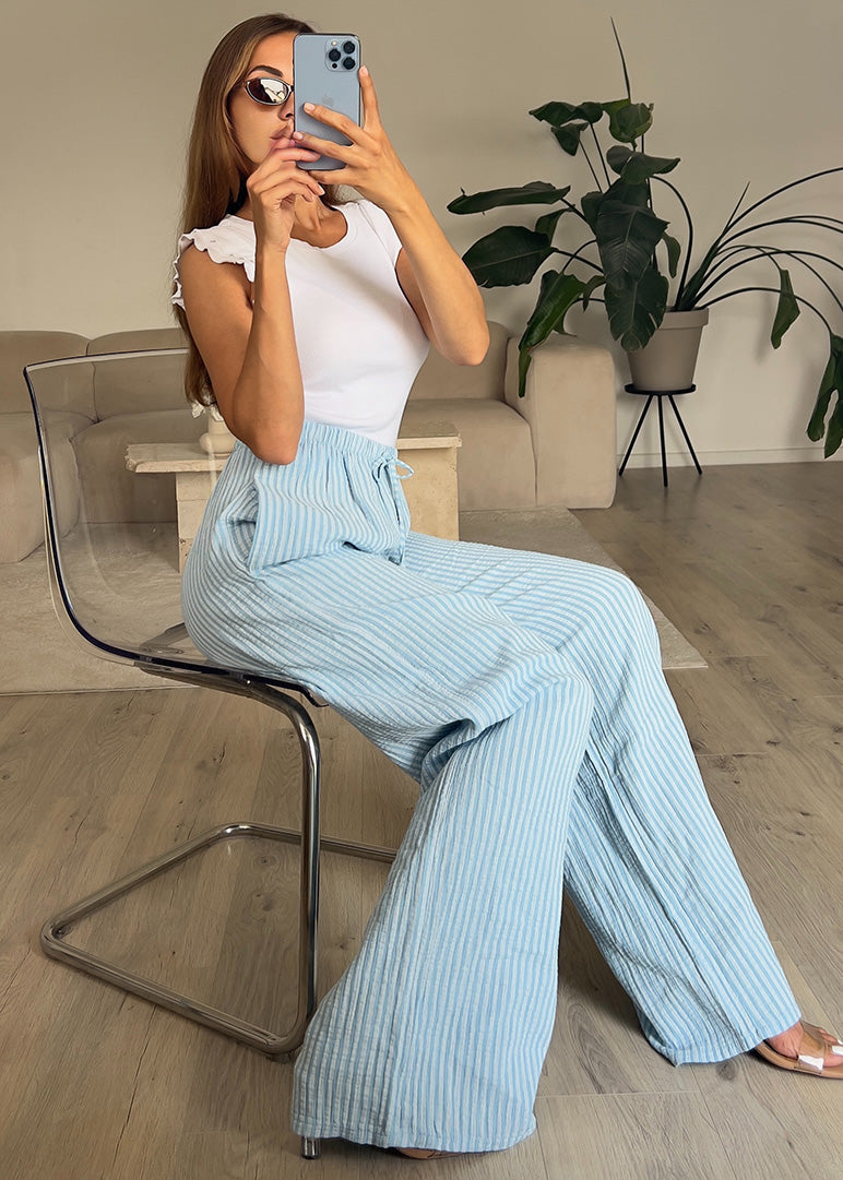 Modell trägt hellblaue Stoffhose mit weißen Streifen und weitem Bein – NAHA Damenhose für Sommer und Alltag.