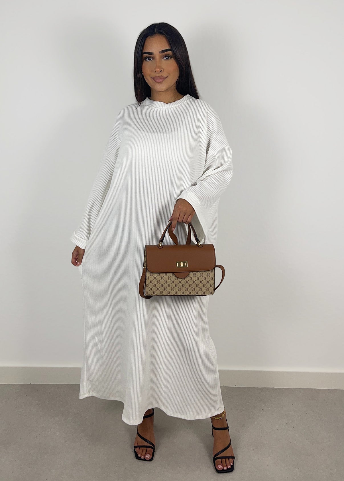 Frau trägt ein geripptes Kleid in Weiß mit figurbetontem Schnitt, frontal fotografiert