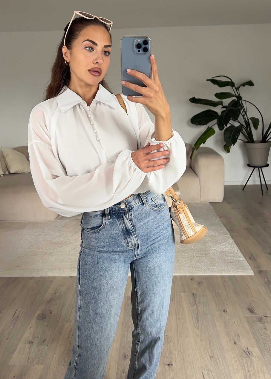 Modell trägt eine weiße Hemdbluse mit klassischem Kragen, Knopfleiste und geradem Schnitt