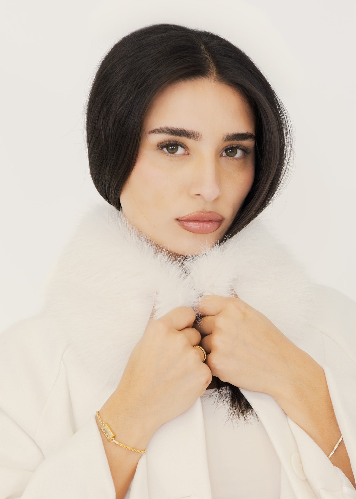 Model hält den weißen Kunstfellkragen der cremefarbenen Cape-Jacke, Nahaufnahme