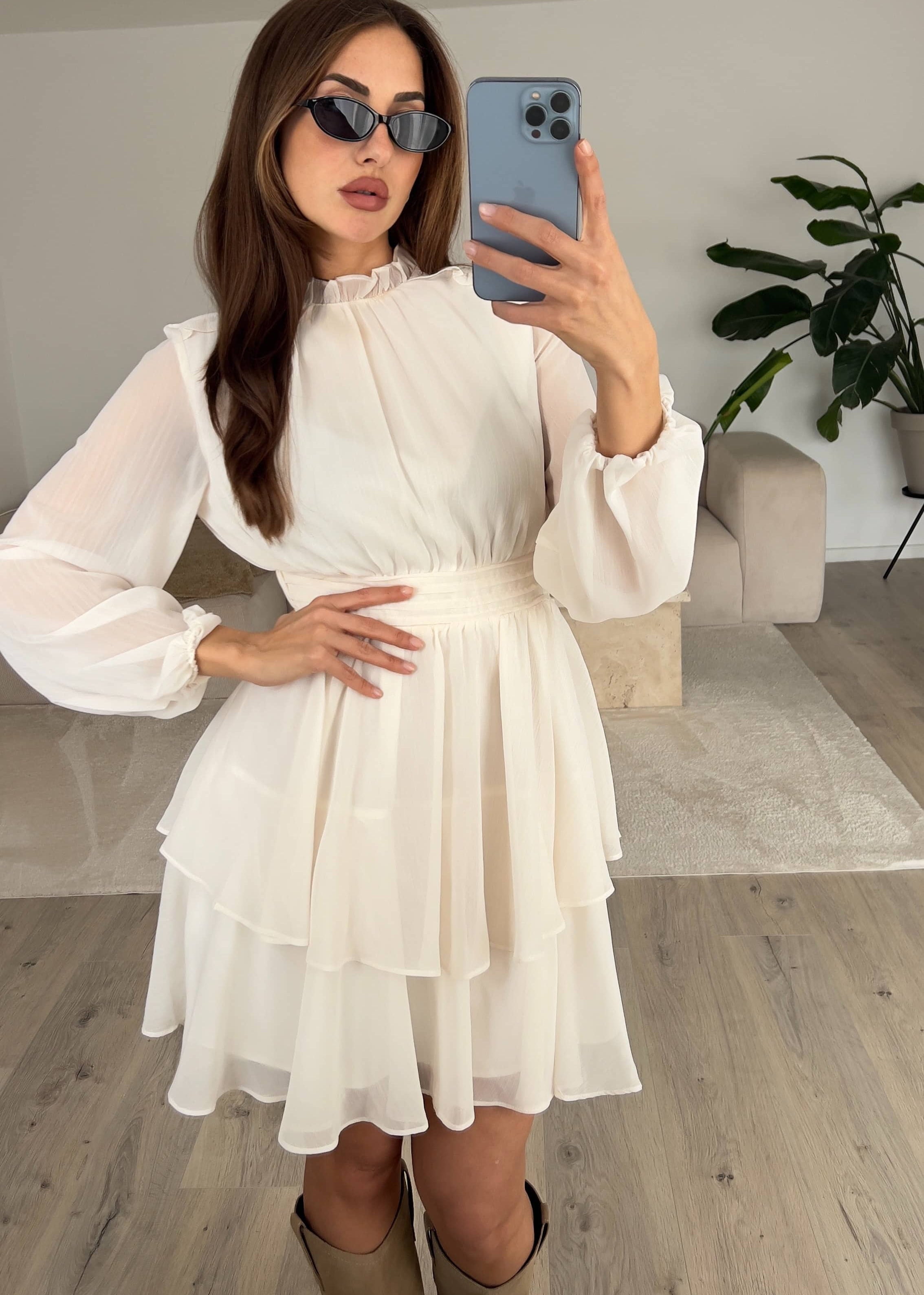 Modell trägt fließendes Kleid mit zarten Rüschen und hochgeschlossenem Kragen – ideal für besondere Anlässe bei NAHA