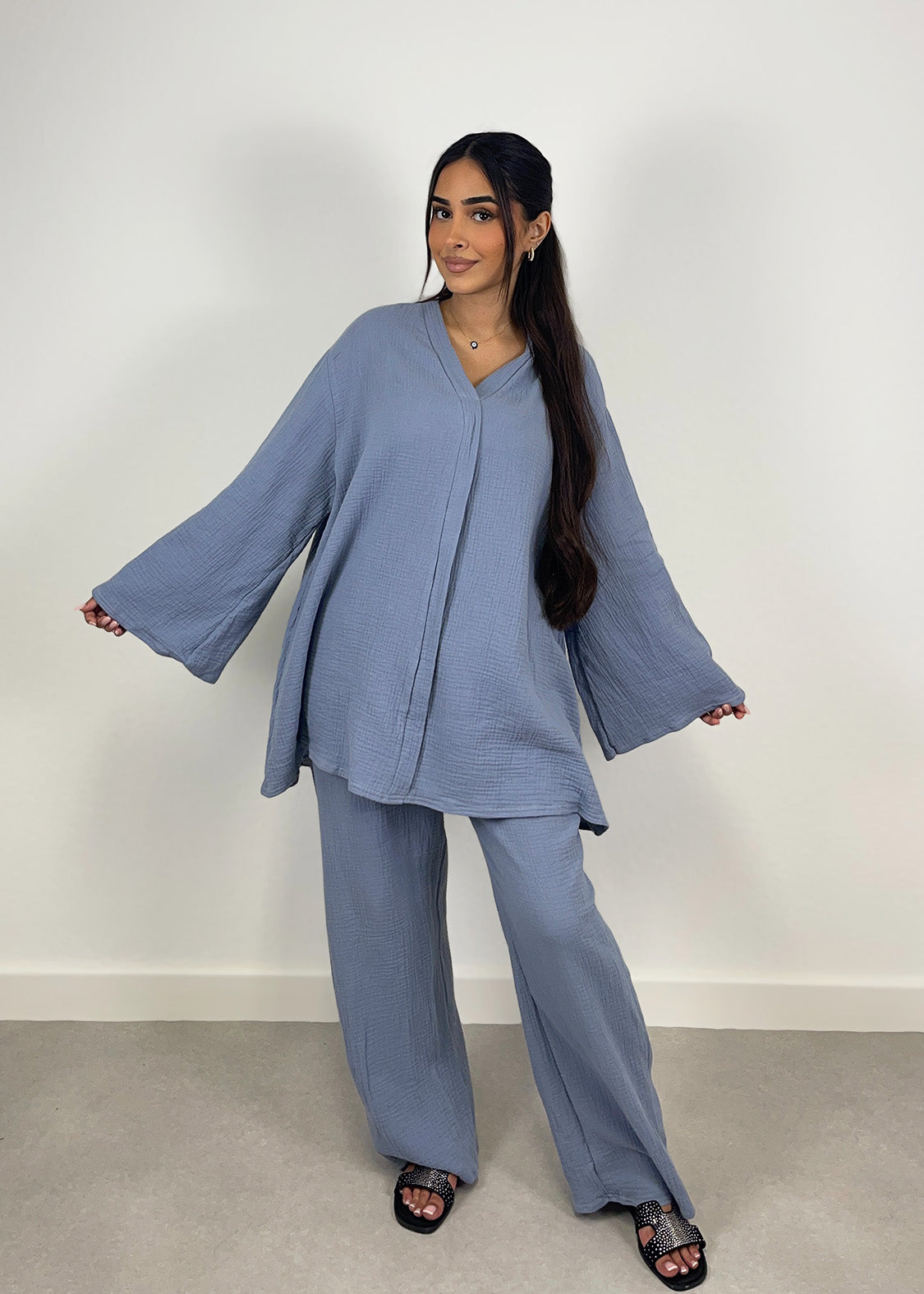 Frau trägt blauen Musselin-Zweiteiler mit Oversize-Bluse und weiter Hose, frontal fotografiert