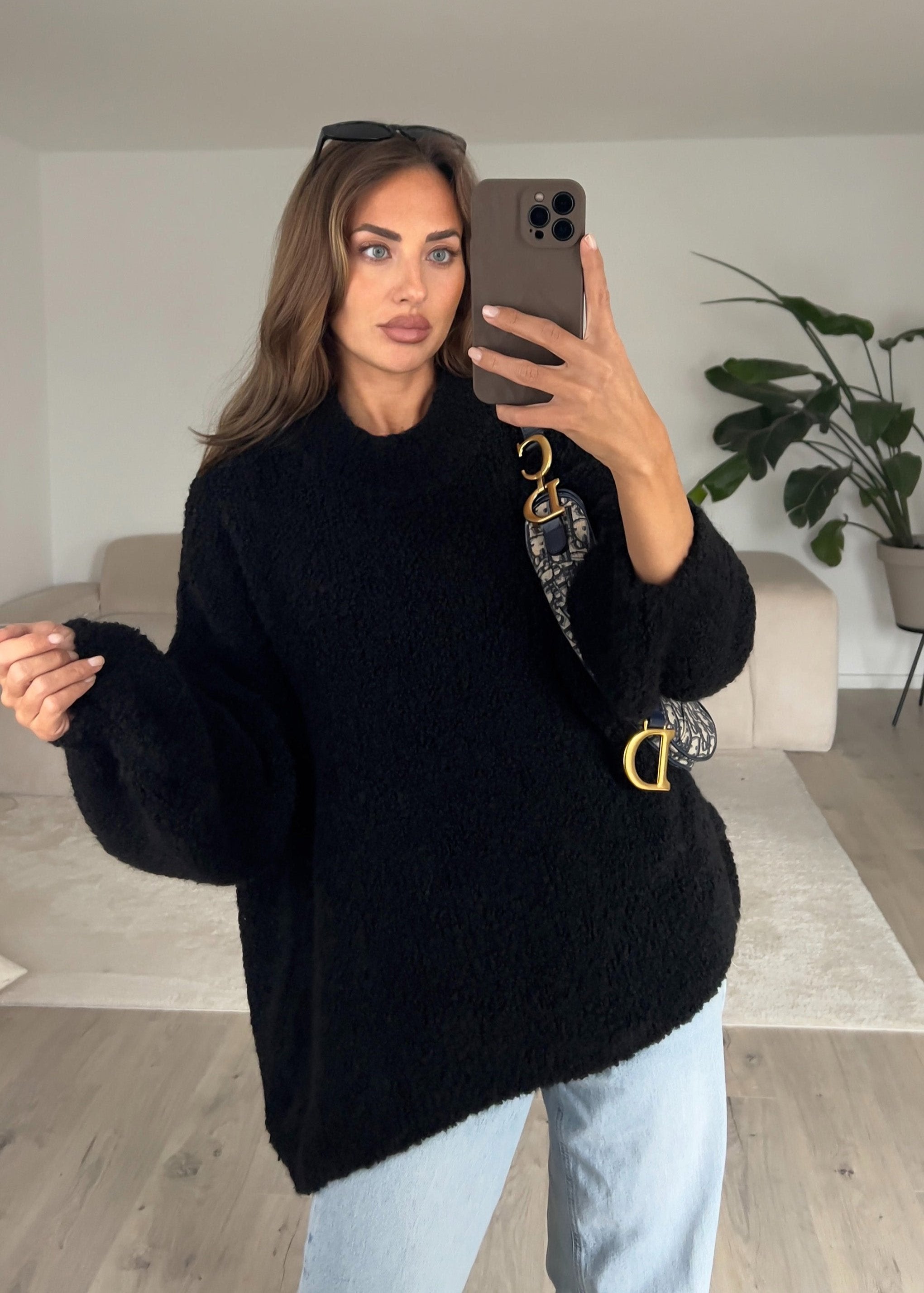 Modell trägt einen schwarzen Bouclé-Pullover mit lockerer Passform und strukturierter Oberfläche