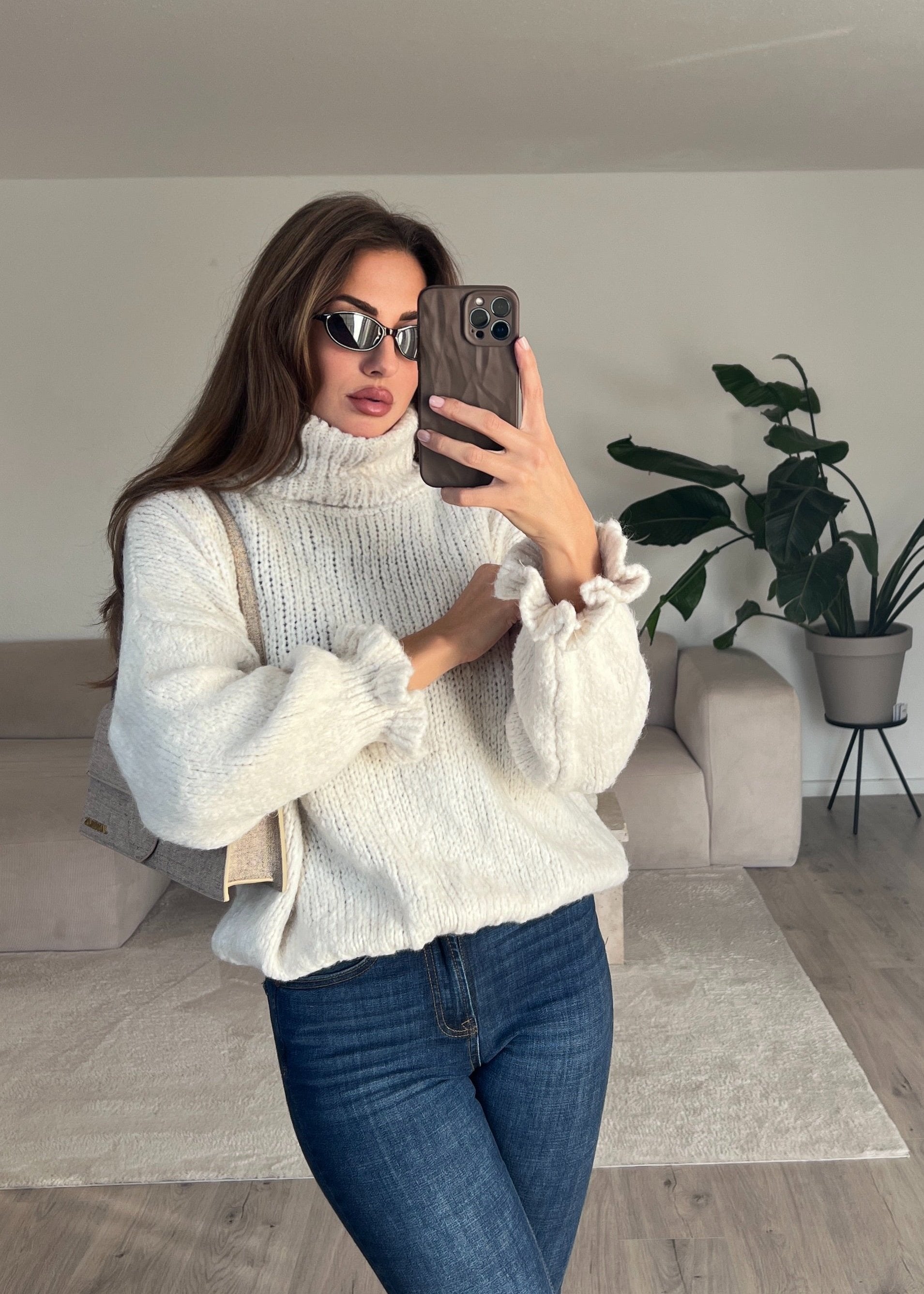 Modell trägt einen beigen Rollkragenpullover mit lockerer Passform und weichem Strick