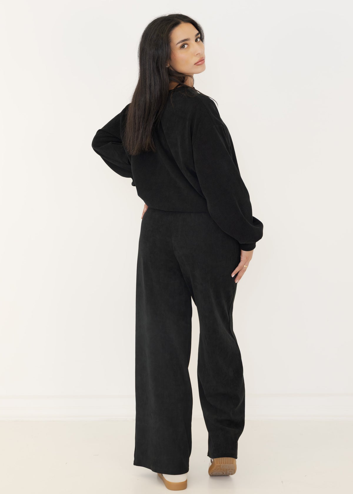 Rückansicht des schwarzen Strick-Sets mit lockerem Pullover und gerader Strickhose