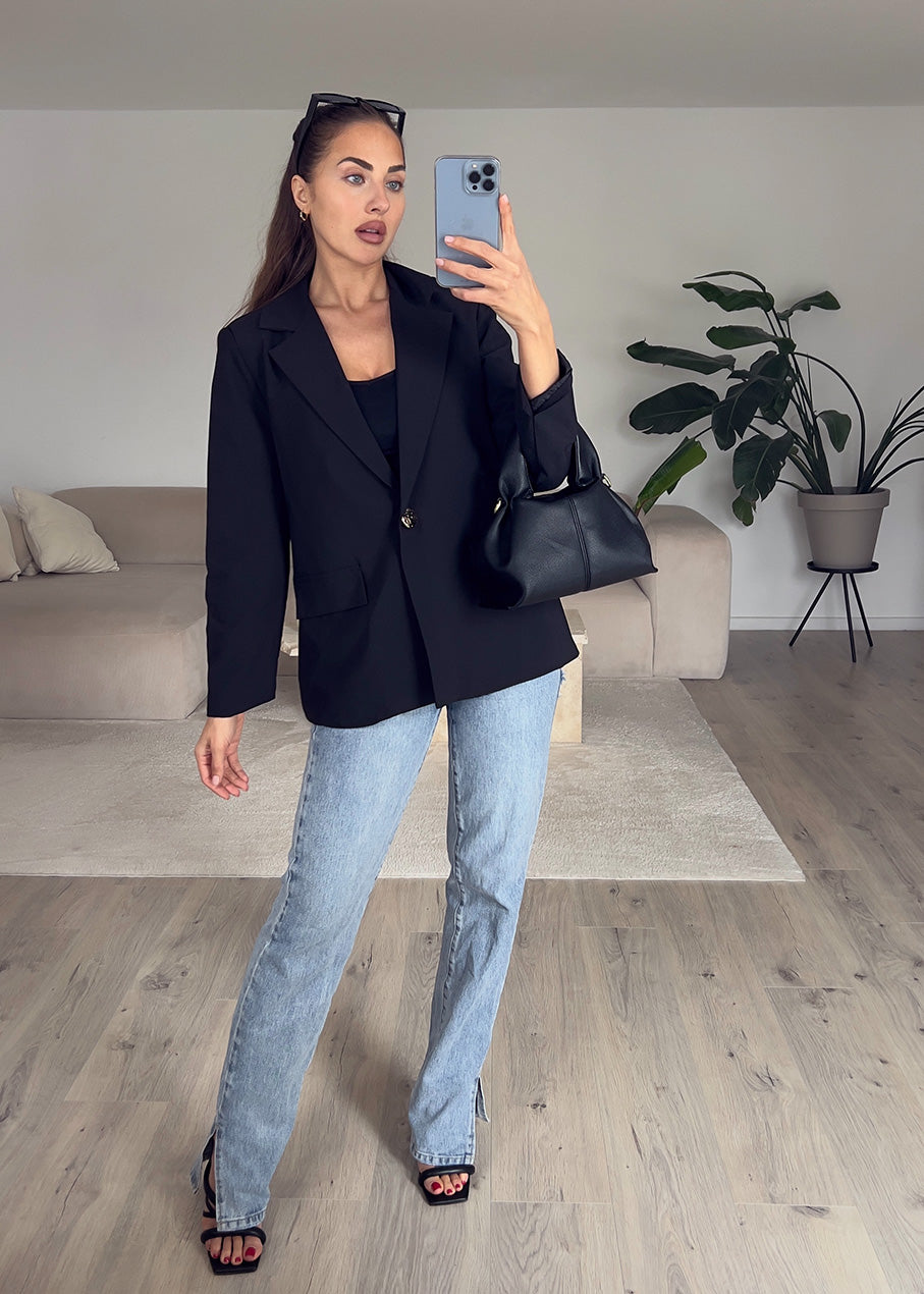 Modell trägt einen schwarzen, taillierten Blazer mit goldfarbenem Knopf – klassischer Look für Alltag & Büro