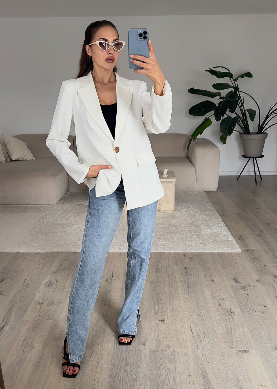 Modell trägt einen weißen, taillierten Blazer mit goldfarbenem Knopf – edler Look für moderne Outfits