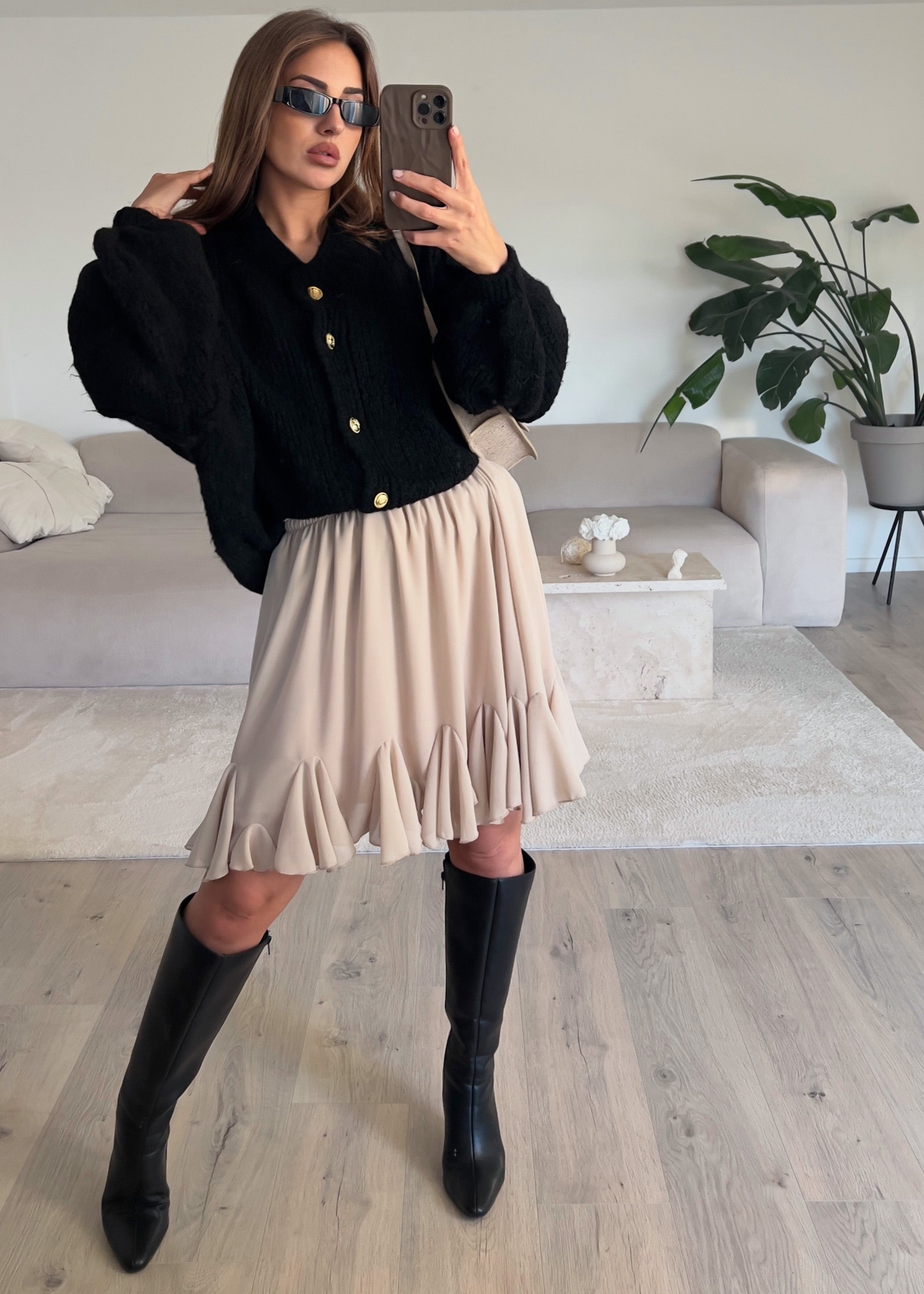 Modell trägt einen luftigen Volantrock in hellem Beige mit Rüschen und fließendem Schnitt – feminin und sommerlich