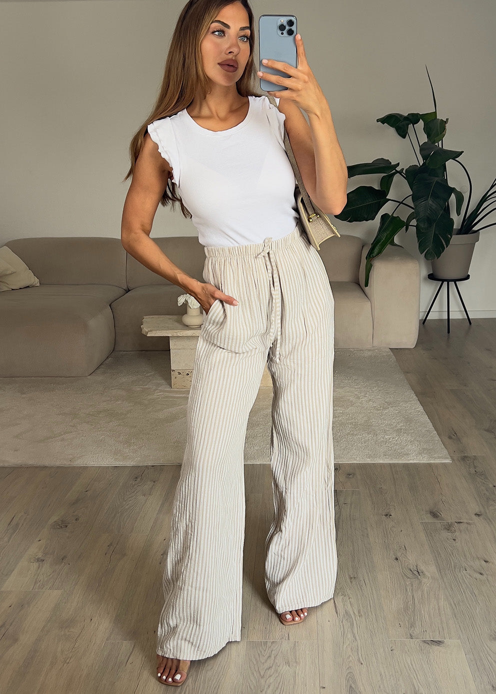 Frau trägt eine weite Musselin Hose in Beige mit feinen Streifen – sommerlicher Look von NAHA