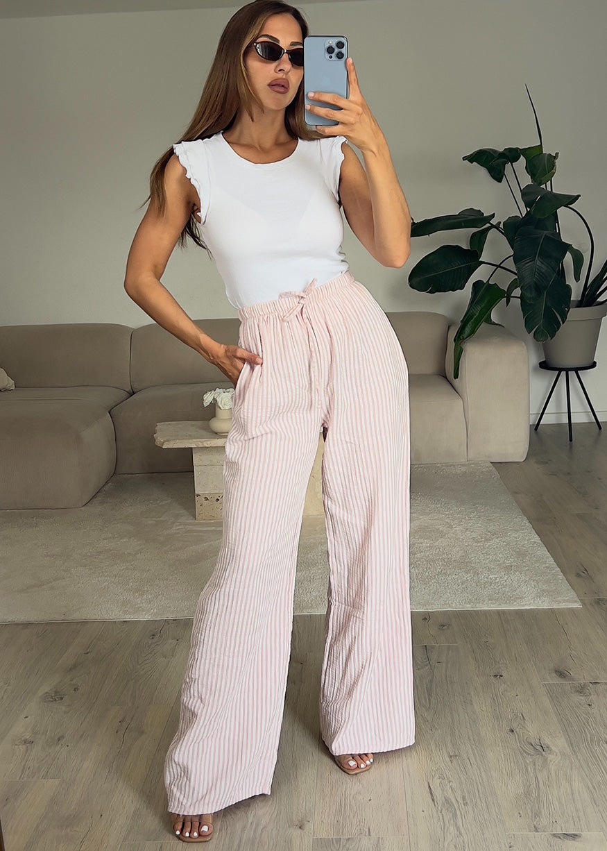 Modell trägt gestreifte Stoffhose mit Bindegürtel – luftiger Sommer-Look für Damen aus der NAHA Stoffhosen-Kollektion.