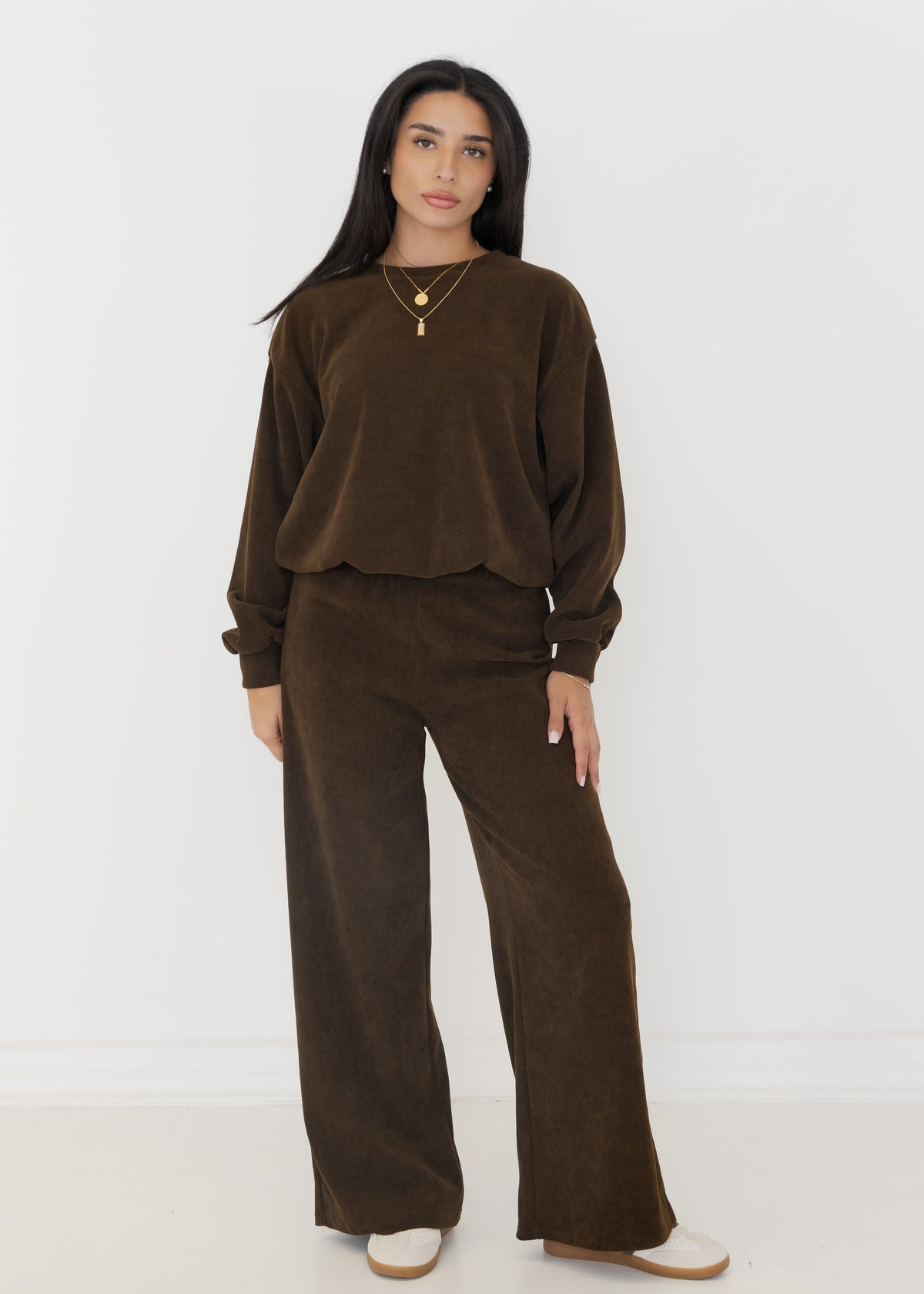 Damen Zweiteiler in Cord-Optik in Schokobraun aus Oversize-Sweatshirt und weiter Hose, getragen mit Sneakern