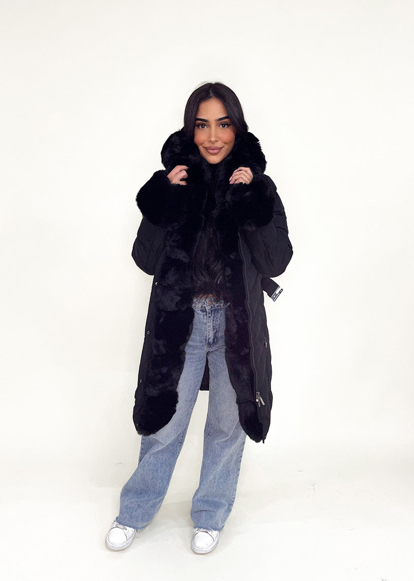 Modell trägt eine taillierte Damen Steppjacke mit Gürtel, Fellkragen und Fellärmeln – NAHA Wintermode