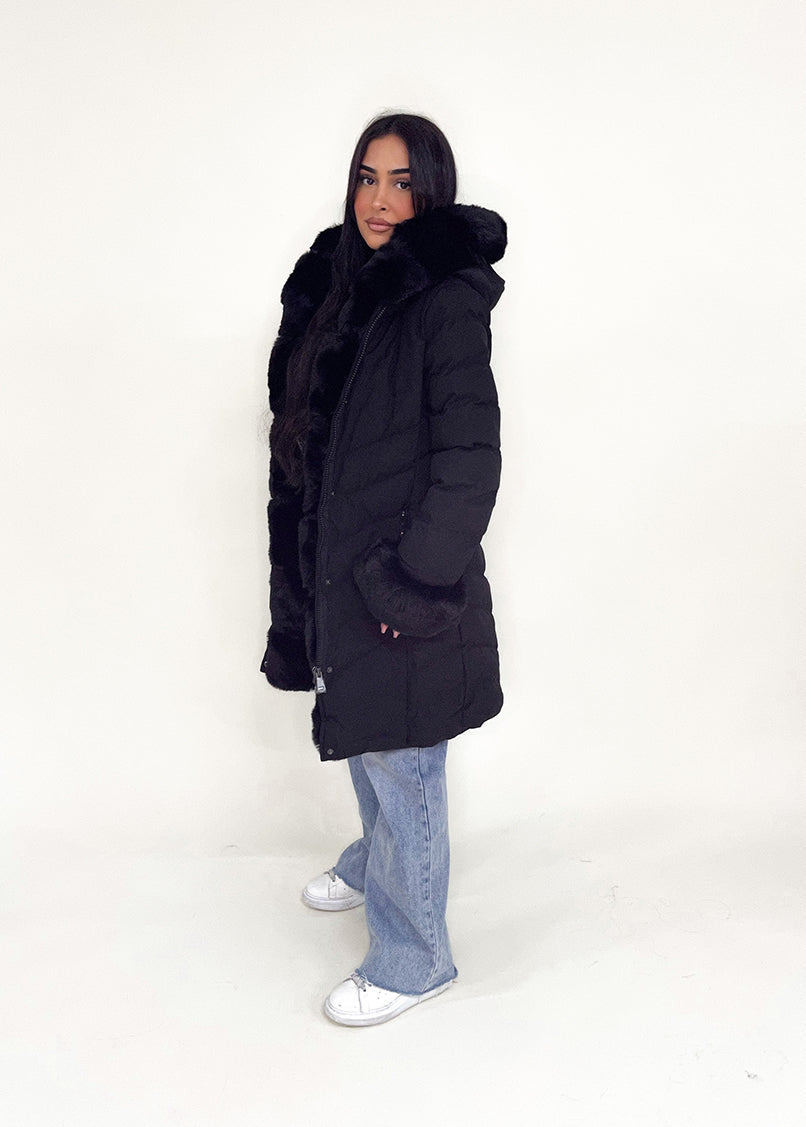 Modell trägt eine taillierte Damen Steppjacke mit Gürtel, Fellkragen und Fellärmeln – NAHA Wintermode