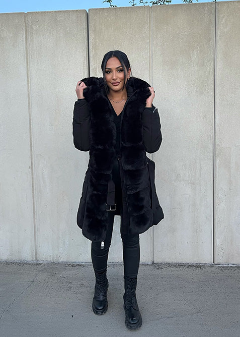 Modell trägt eine taillierte Damen Steppjacke mit Kunstfellbesatz und Gürtel – NAHA Fashion