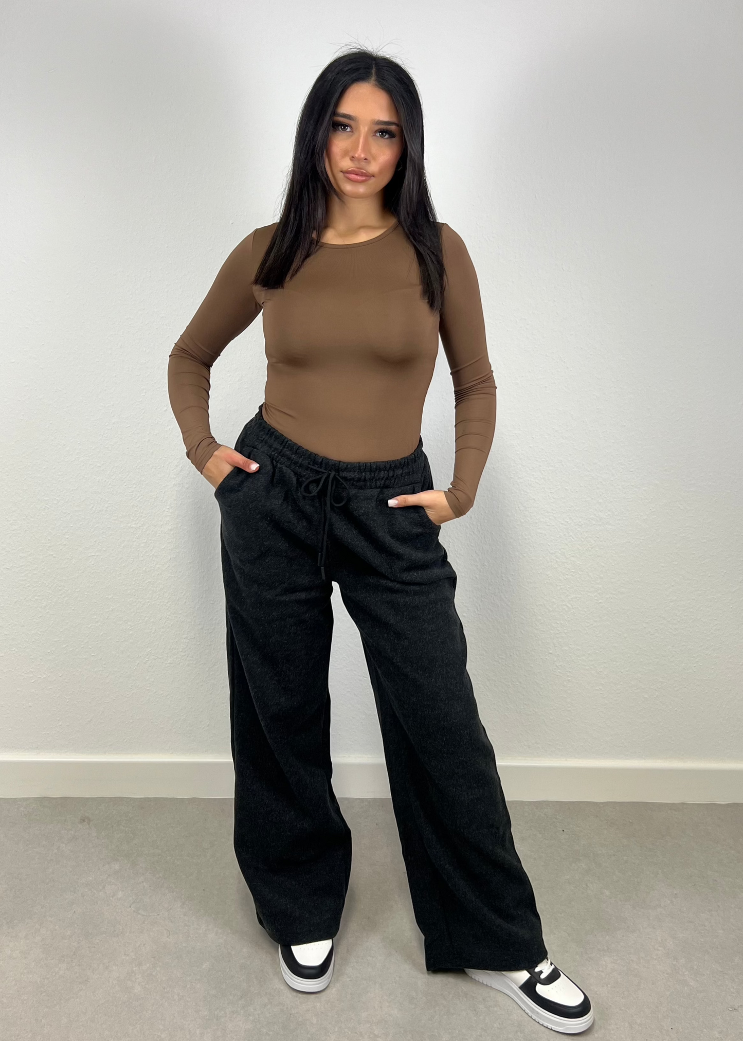 Frau trägt schwarze Straight Sweat Pants mit elastischem Bund – sportlich-cleaner Look von NAHA

