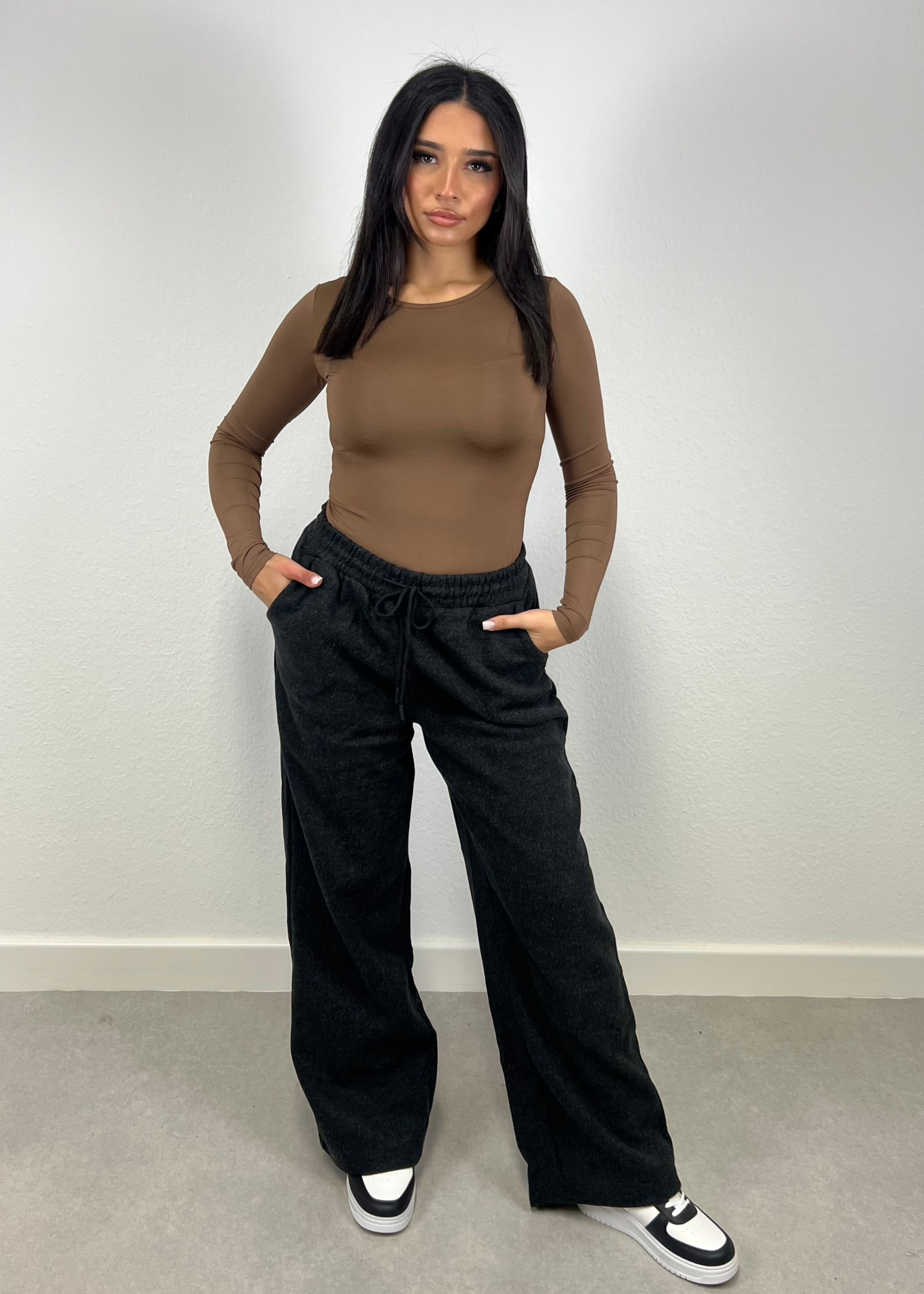 Frau trägt schwarze Straight Sweat Pants mit elastischem Bund – sportlich-cleaner Look von NAHA

