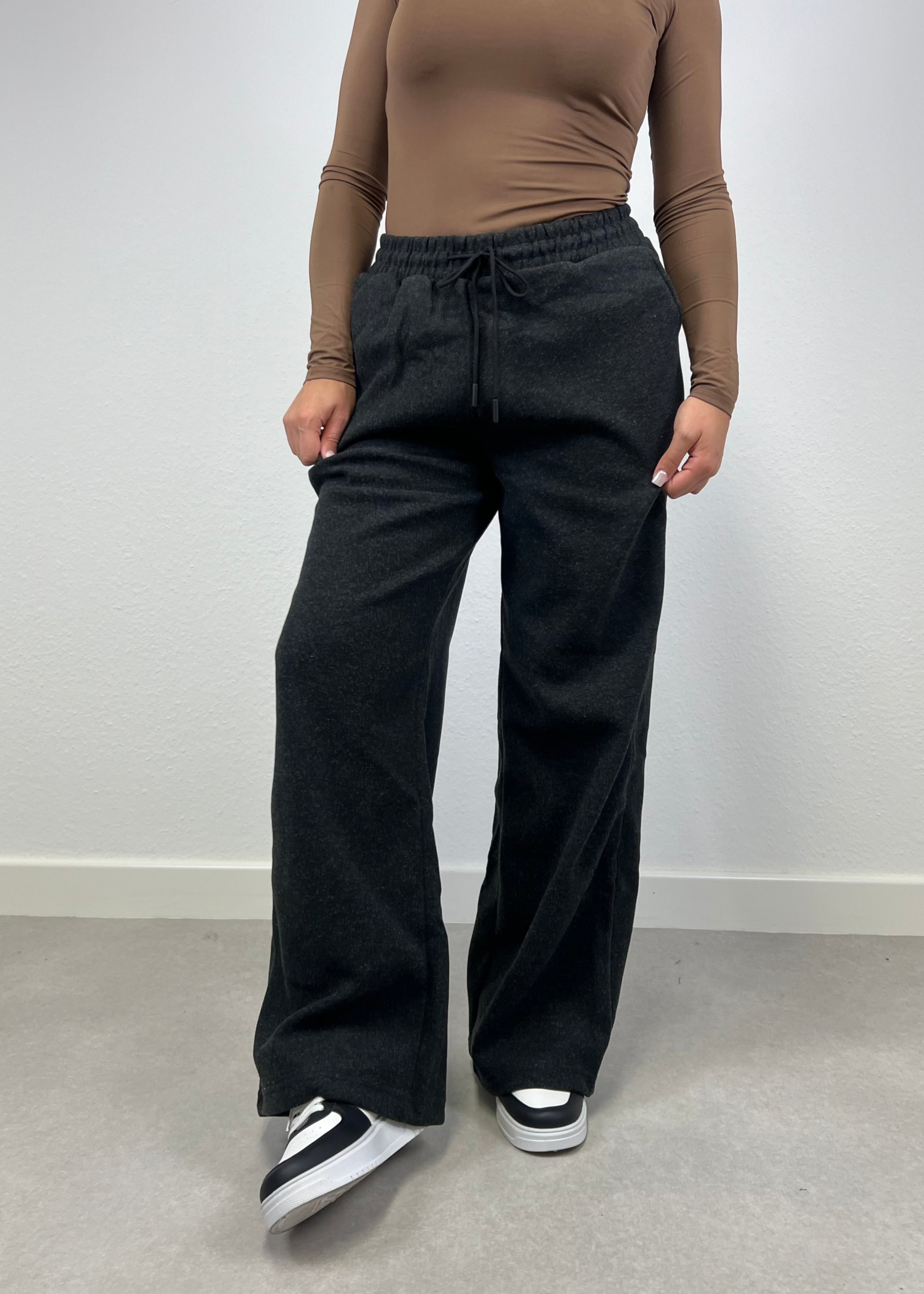 Frau trägt schwarze Straight Sweat Pants mit elastischem Bund – sportlich-cleaner Look von NAHA

