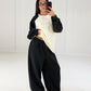 Model hebt das Sweatshirt an und zeigt den elastischen Bund der schwarzen Ballonhose