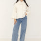 Damen Cape-Jacke in Creme mit weißem Kunstfellkragen, geknöpft getragen zu heller Wide-Leg-Jeans