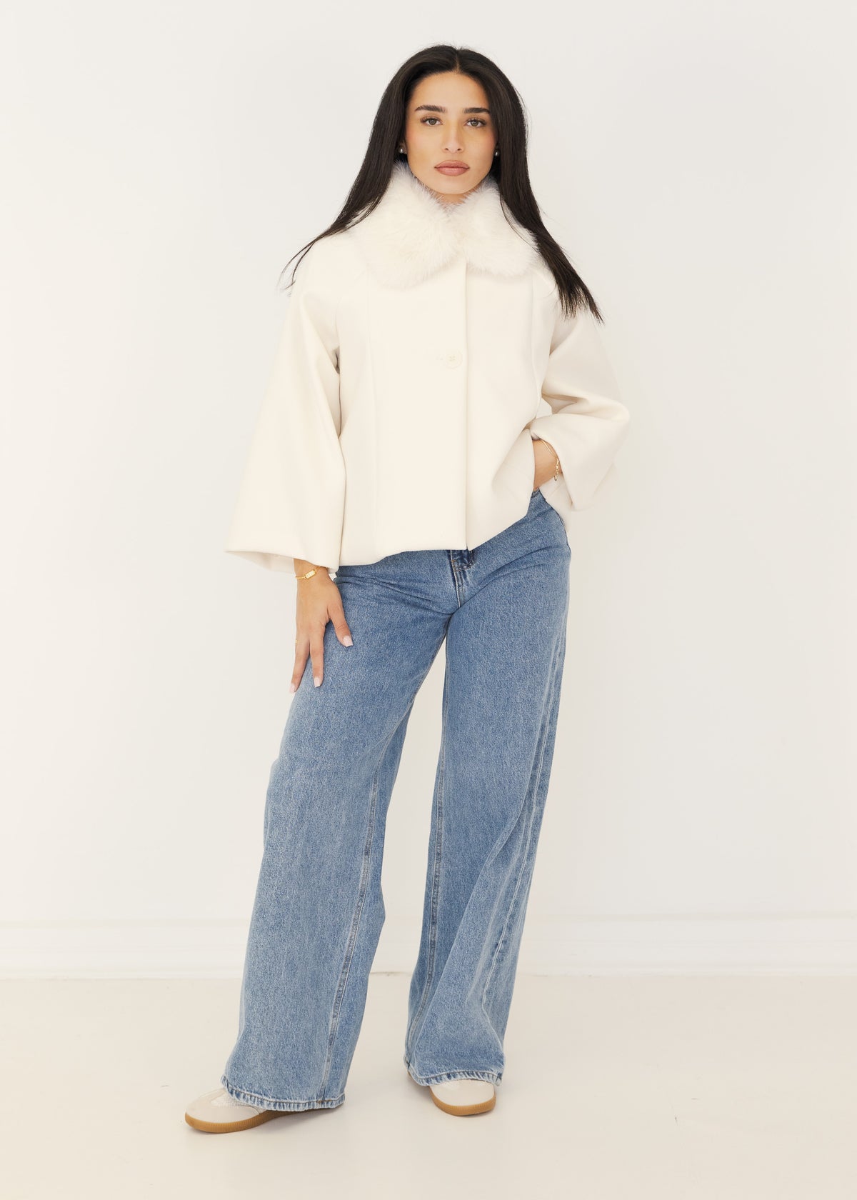 Damen Cape-Jacke in Creme mit weißem Kunstfellkragen, geknöpft getragen zu heller Wide-Leg-Jeans