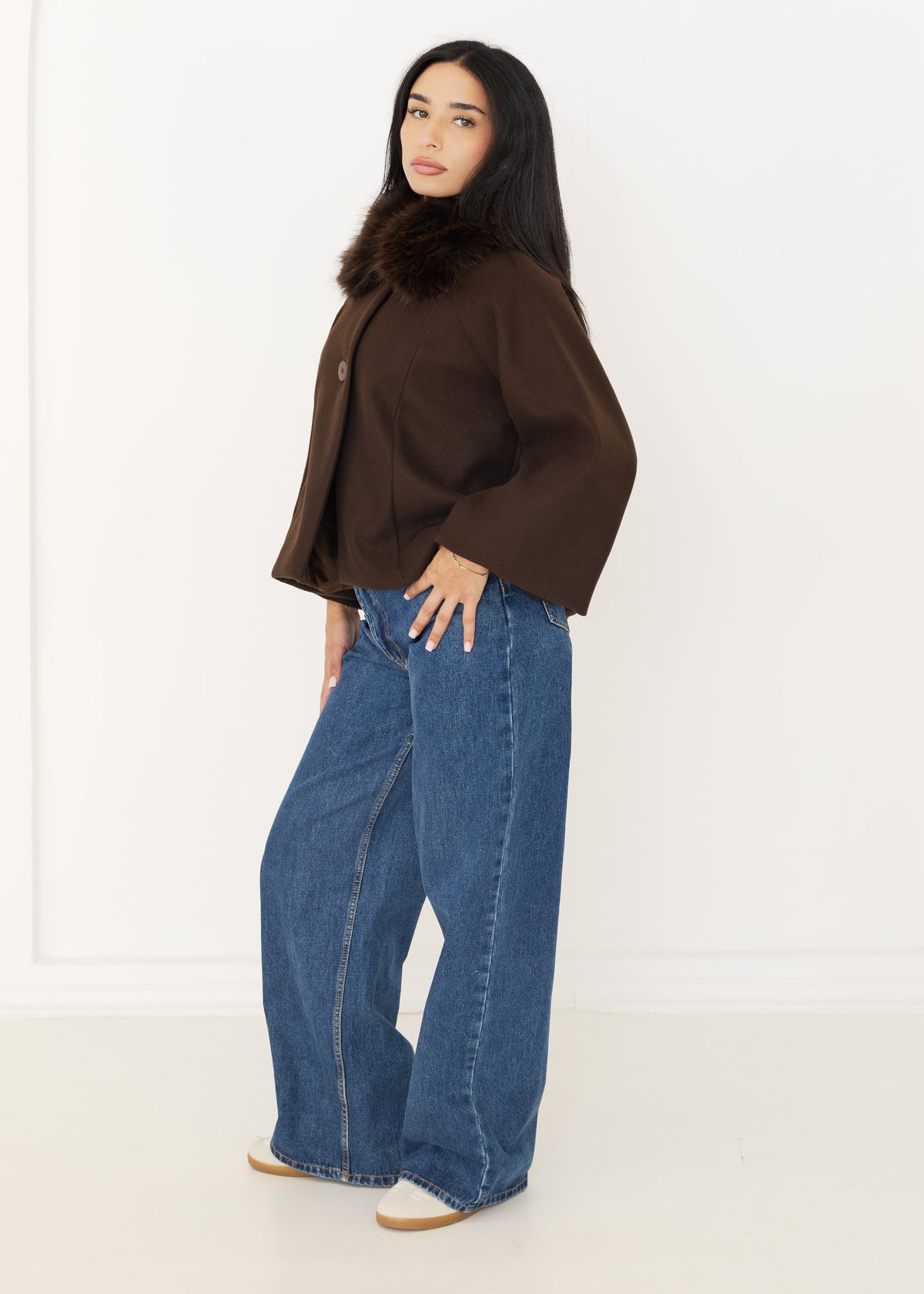 Seitenansicht der braunen Cape-Jacke mit Fellkragen, cropped Länge und Oversize-Ärmeln