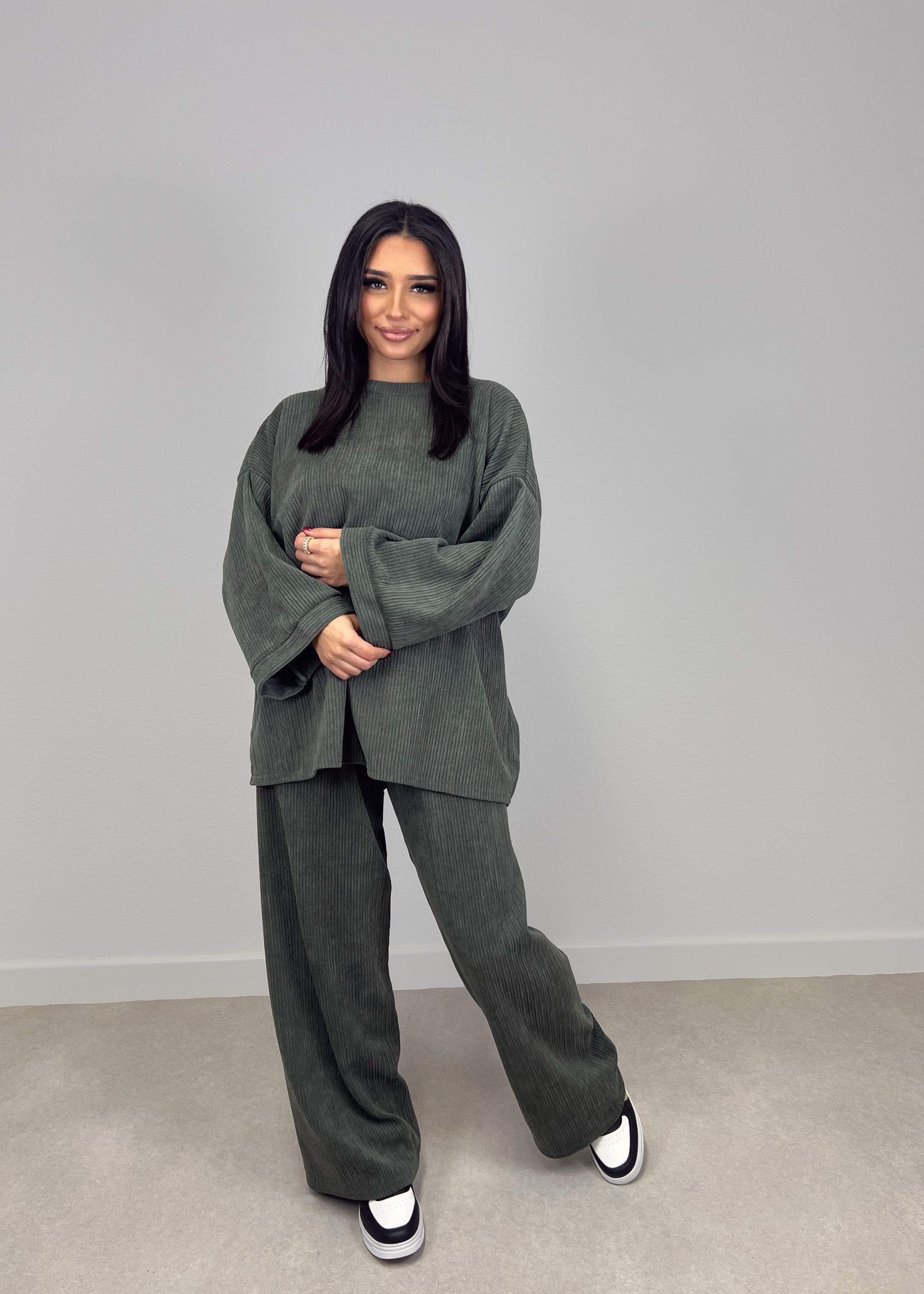 Modell trägt NAHA Cord-Zweiteiler in Khaki mit Oversize-Oberteil und gerader Hose – bequemer Streetstyle-Look mit Struktur.

