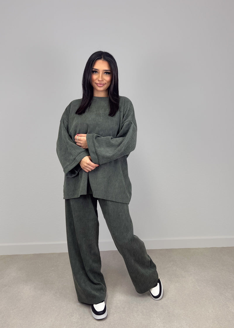 Modell trägt NAHA Cord-Zweiteiler in Khaki mit Oversize-Oberteil und gerader Hose – bequemer Streetstyle-Look mit Struktur.

