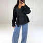 Frau in schwarzem Cropped Trenchcoat mit Bindegürtel zu Wide-Leg-Jeans, ganze Figur