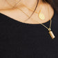 Detailansicht des schwarzen Feinstricks am Ausschnitt mit Goldschmuck