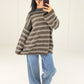 Frau in braunem Oversize-Strickpullover mit cremefarbenen Streifen zu Wide-Leg-Jeans