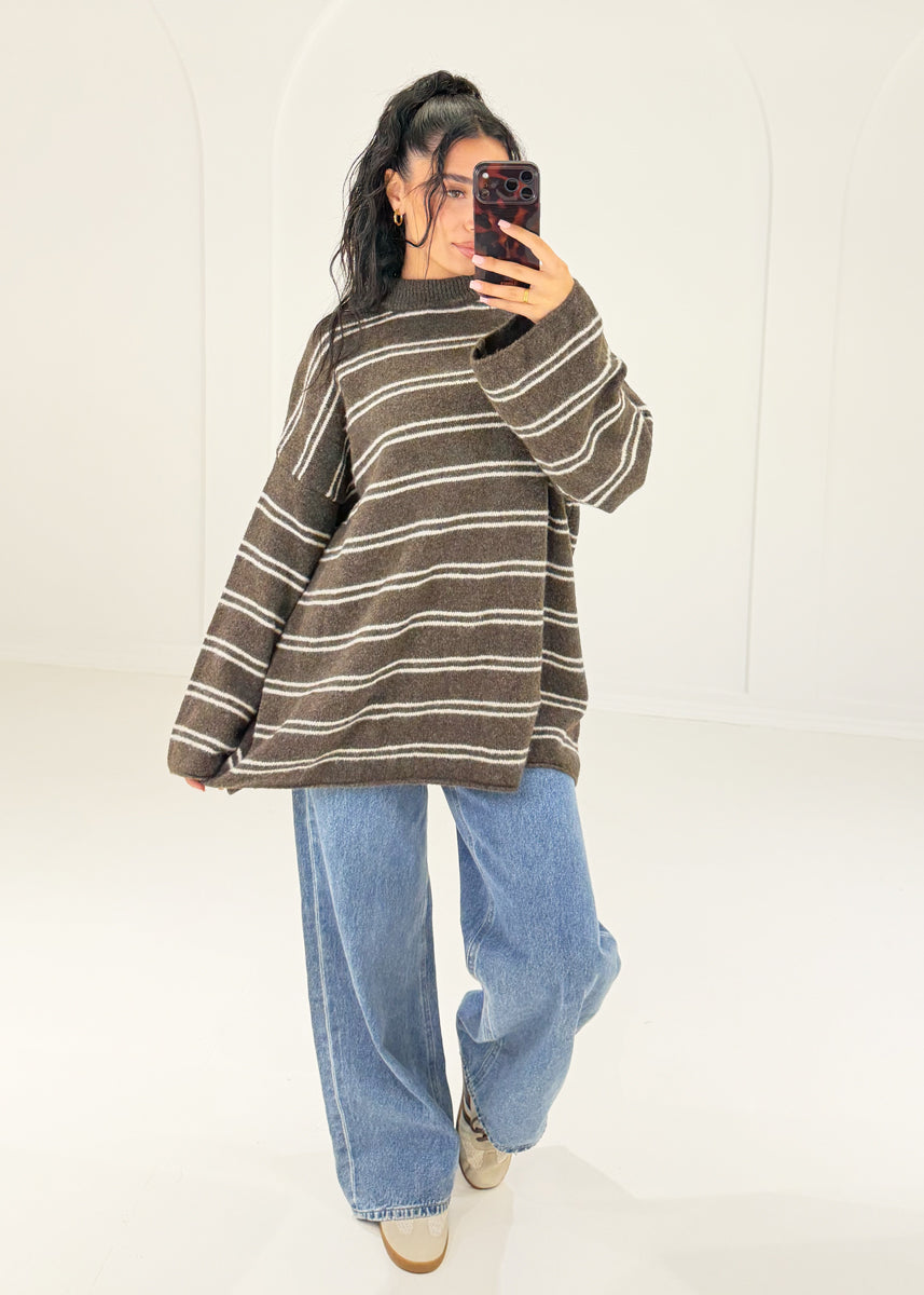 Frau in braunem Oversize-Strickpullover mit cremefarbenen Streifen zu Wide-Leg-Jeans