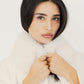 Model hält den weißen Kunstfellkragen der cremefarbenen Cape-Jacke, Nahaufnahme