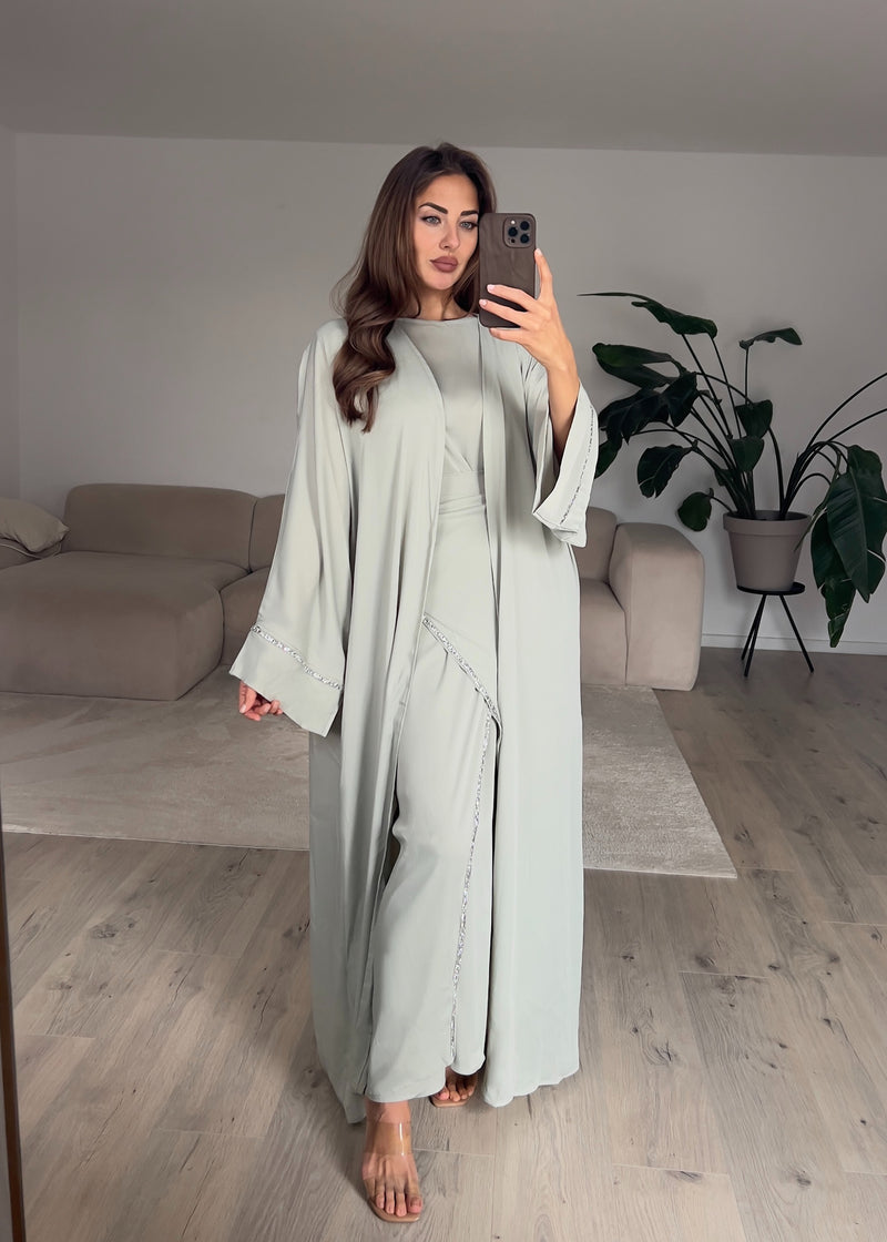 Modell trägt ein mintfarbenes, zweiteiliges Kaftankleid mit Wickelrock und lockerem Oberteil – eleganter Look mit leichtem Fall