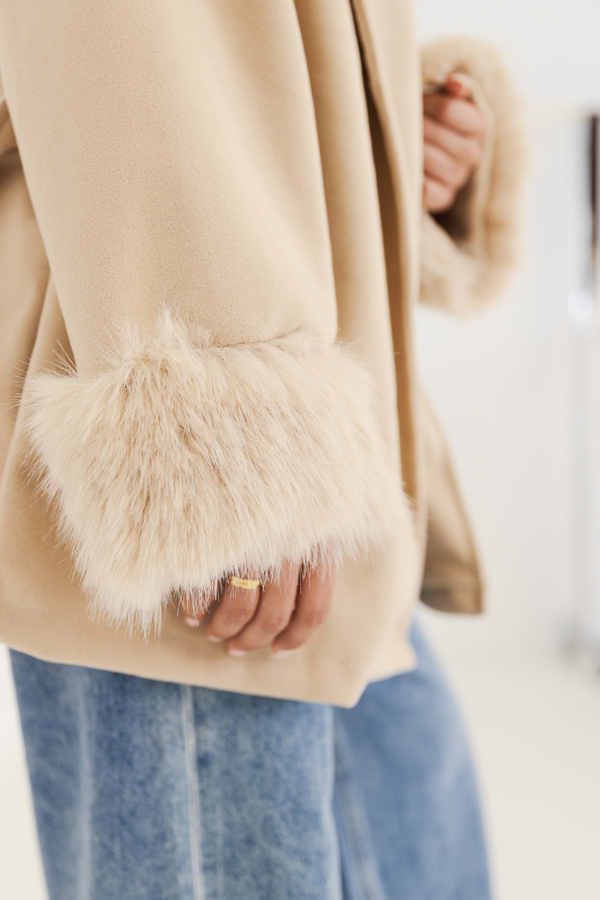 Detailansicht der flauschigen Kunstfell-Manschette am Ärmel der beigen Wickeljacke