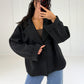 Frau in kurzem schwarzem Zweireiher-Mantel geschlossen zu Wide-Leg-Jeans, Nachaufnahme
