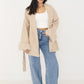 Offen getragener beiger Kurzmantel mit Schalkragen über weißem Crop-Top und Jeans